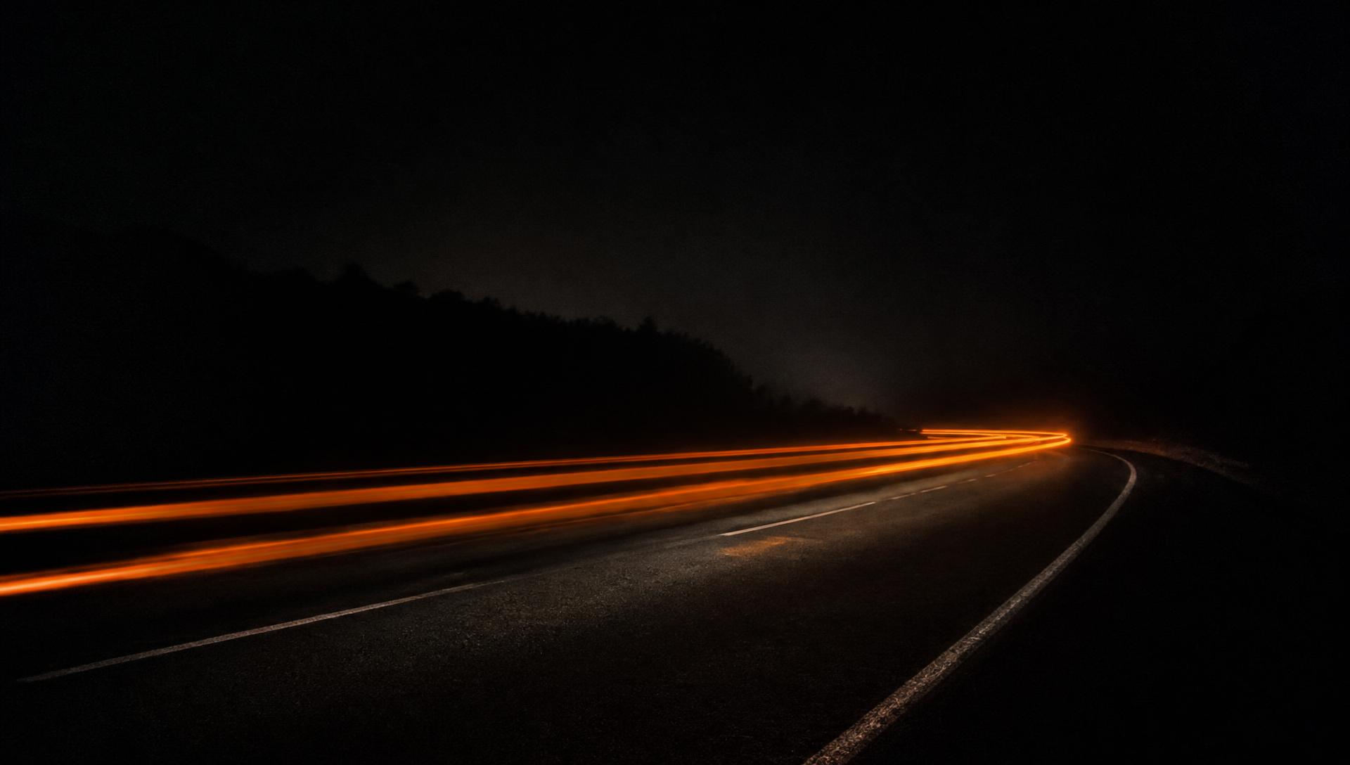 Orange light trails on a dark road at night